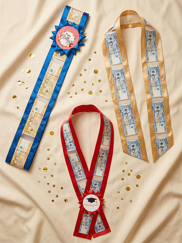Money lei collection — red money lei, blue money sash, and gold money stole with Philippine peso bills and custom rosette accents